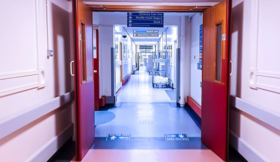 Looking down a hospital corridor through open doors.