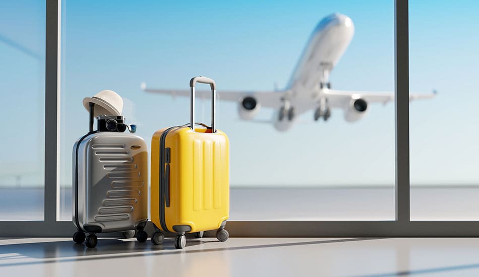 Luggage in airport by window with a plane taking off from runway in the background.