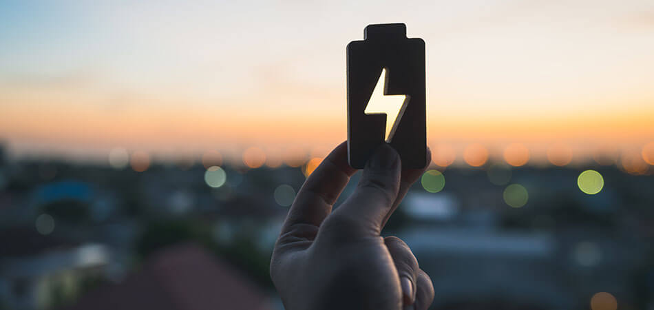 Battery shape being held up to a sunset in the distance.