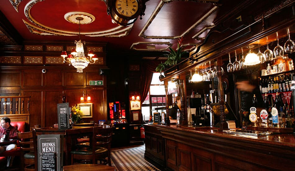 Inside a pub looking towards the bar with a seating area at the side.