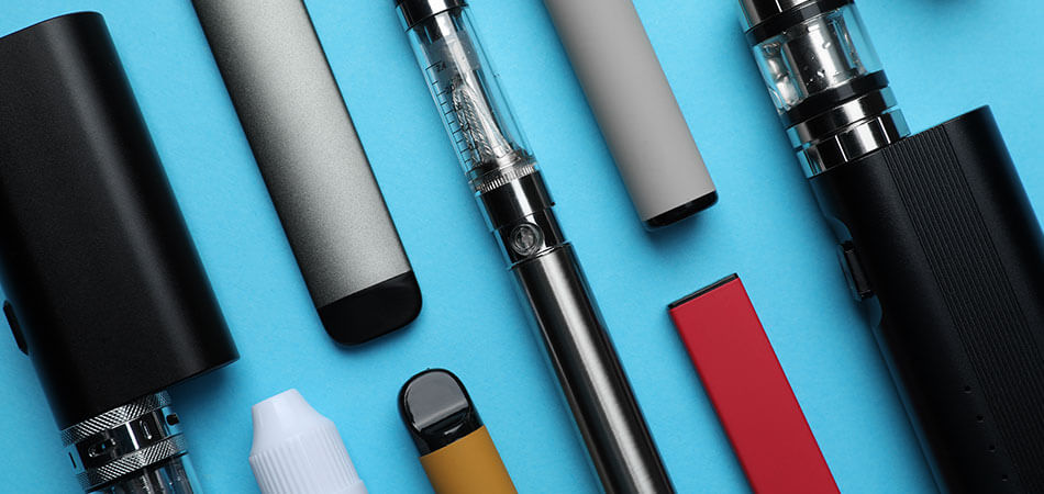 Flat lay image of multiple vape devices, including pods kits and disposable vapes.