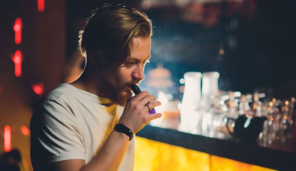 Man vaping e-cigarette inside a bar venue.