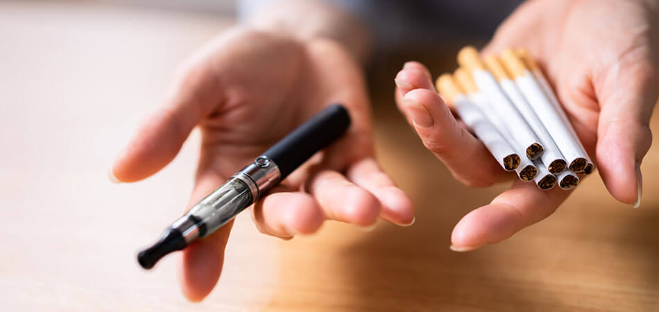 e-cigarette in one hand and cigarettes in the other.