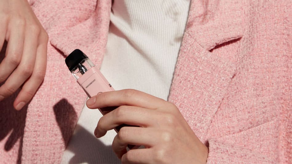 Woman wearing pink jacket and holding pink Xros vape kit in her left hand.
