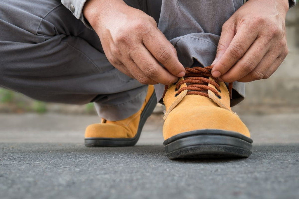 Homme faisant lacets chaussures de sécurité