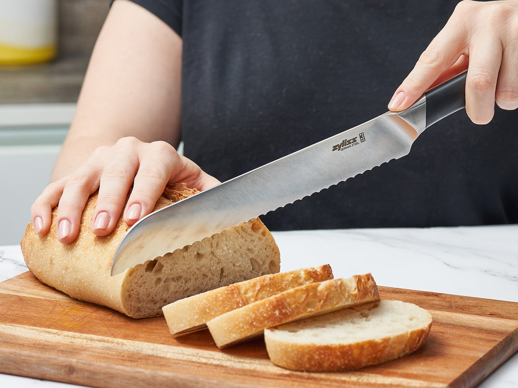 bread knife cutting a loaf of bread on a wooden chopping board