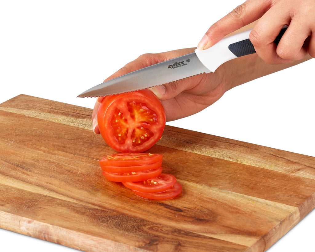 serrated knife cutting a tomato 