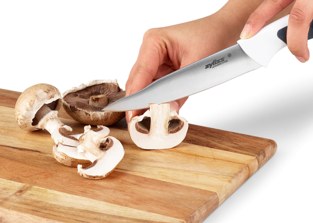 utility knife chopping mushrooms on a wooden chopping board