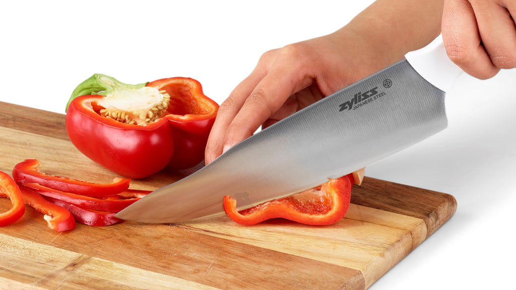 Chef's knife cutting peppers on a wooden board