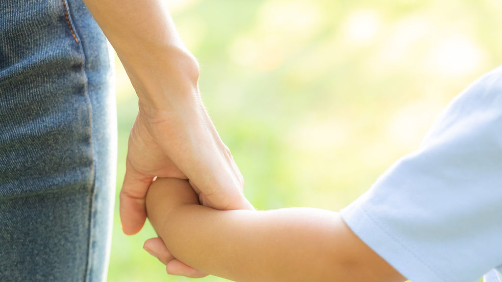 close up of a child and an adult holding hands