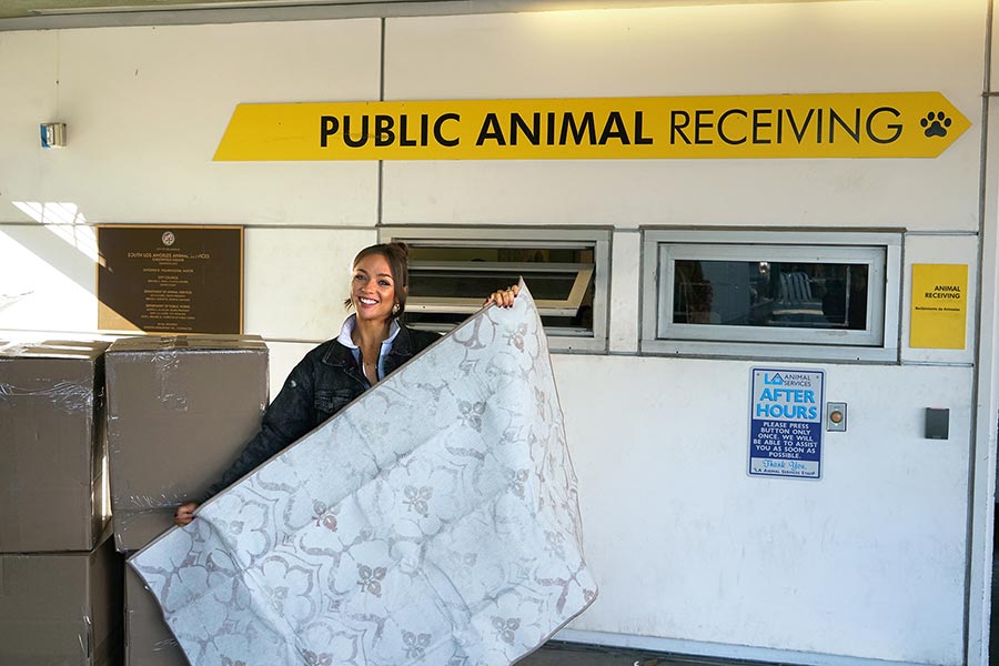 Monica Dallyn the co-founder of My Magic Carpet machine washable rugs, holds the Leilani Damask Ivory washable rug at the South Los Angeles Animal Shelter