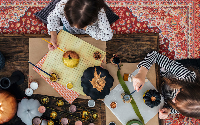 Children sitting around a table feeling pumpkins on a Kenya Ruby washable rug.