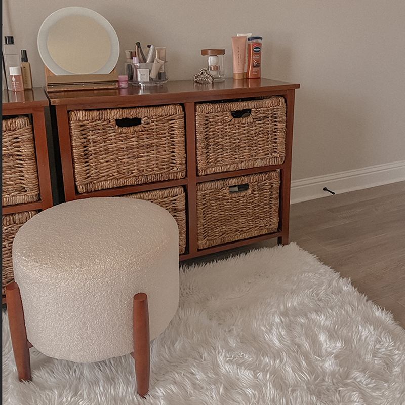 White washable shag rug with a short stool and a wicker dresser.
