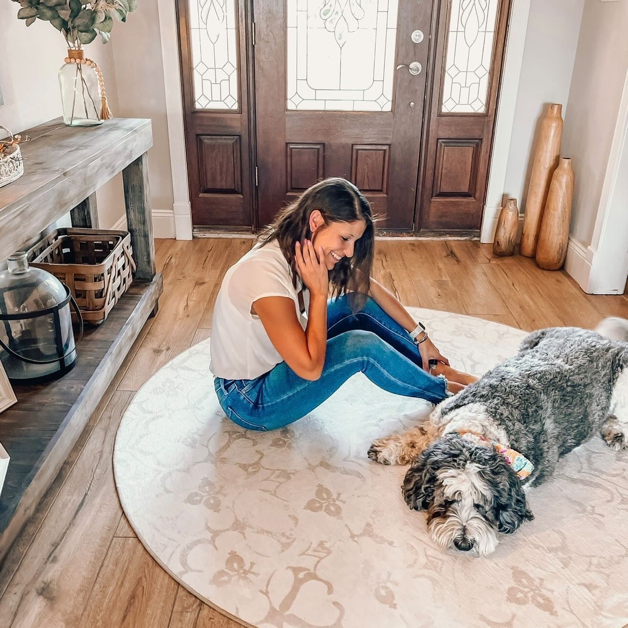 Woman and dog on a round carpet in house entryway