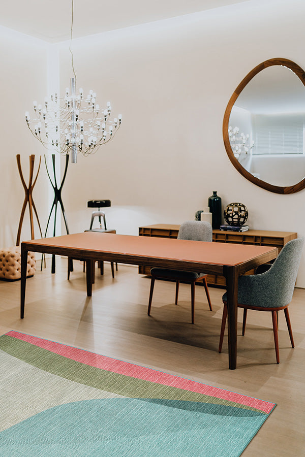 Modern dining room with wood table, wool covered chairs, a large irregular shaped mirror, washable rug and other decor.