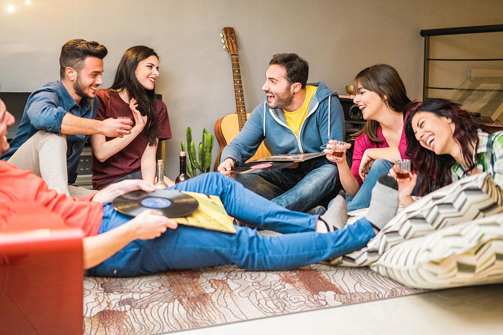 A group of friends sitting on the My Magic Carpet Vienna Abstract washable rug.