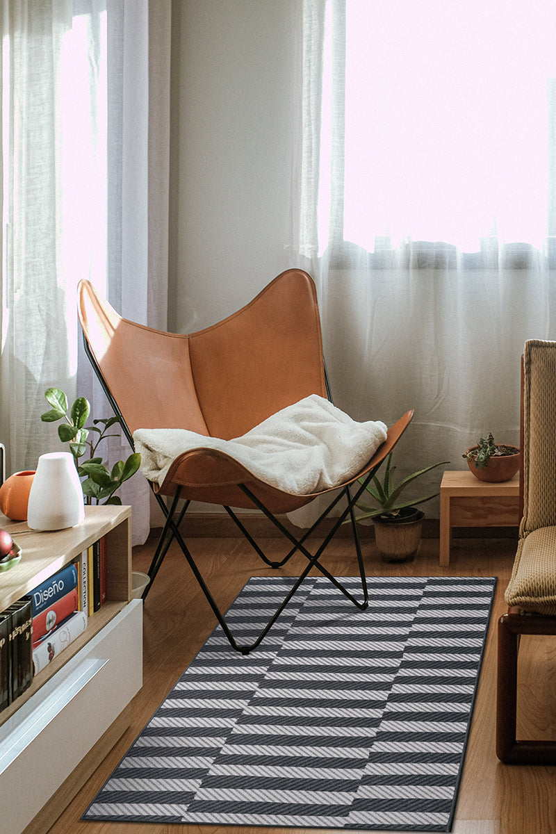 Striped washable rug on a corner living room floor under a quad chair next to curtained windows. 