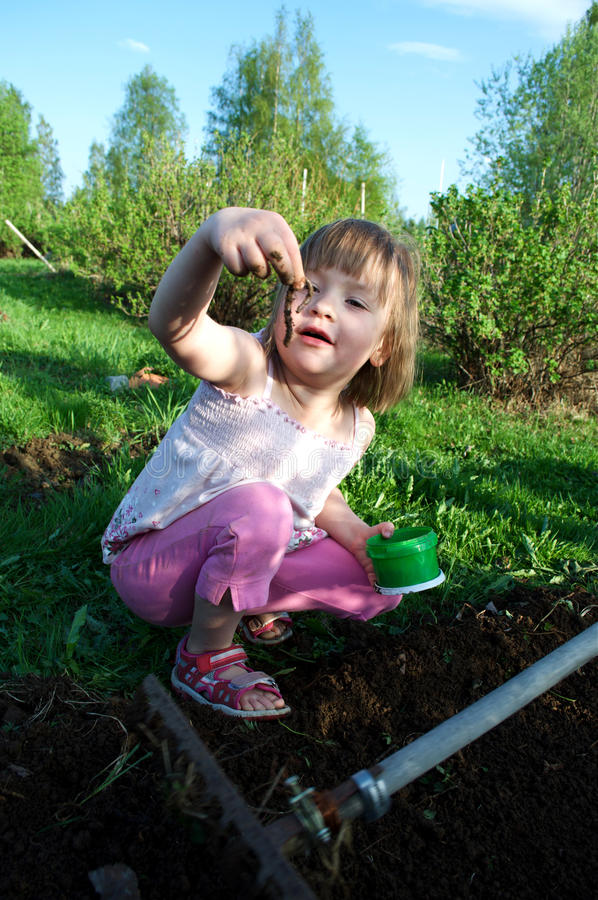 Young girl holding a worm in a garden