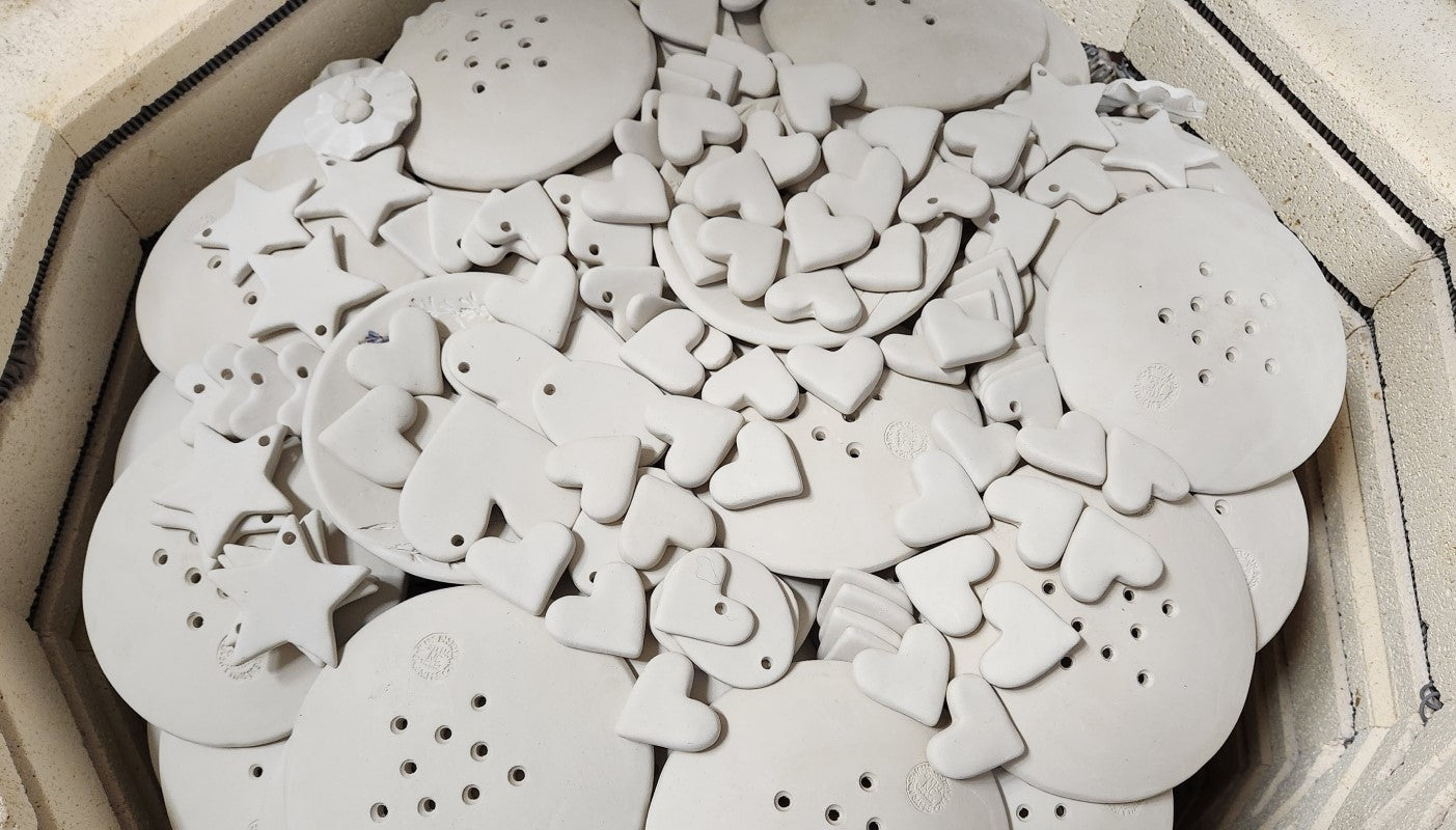 The image shows a stack of unfired pottery inside a kiln.