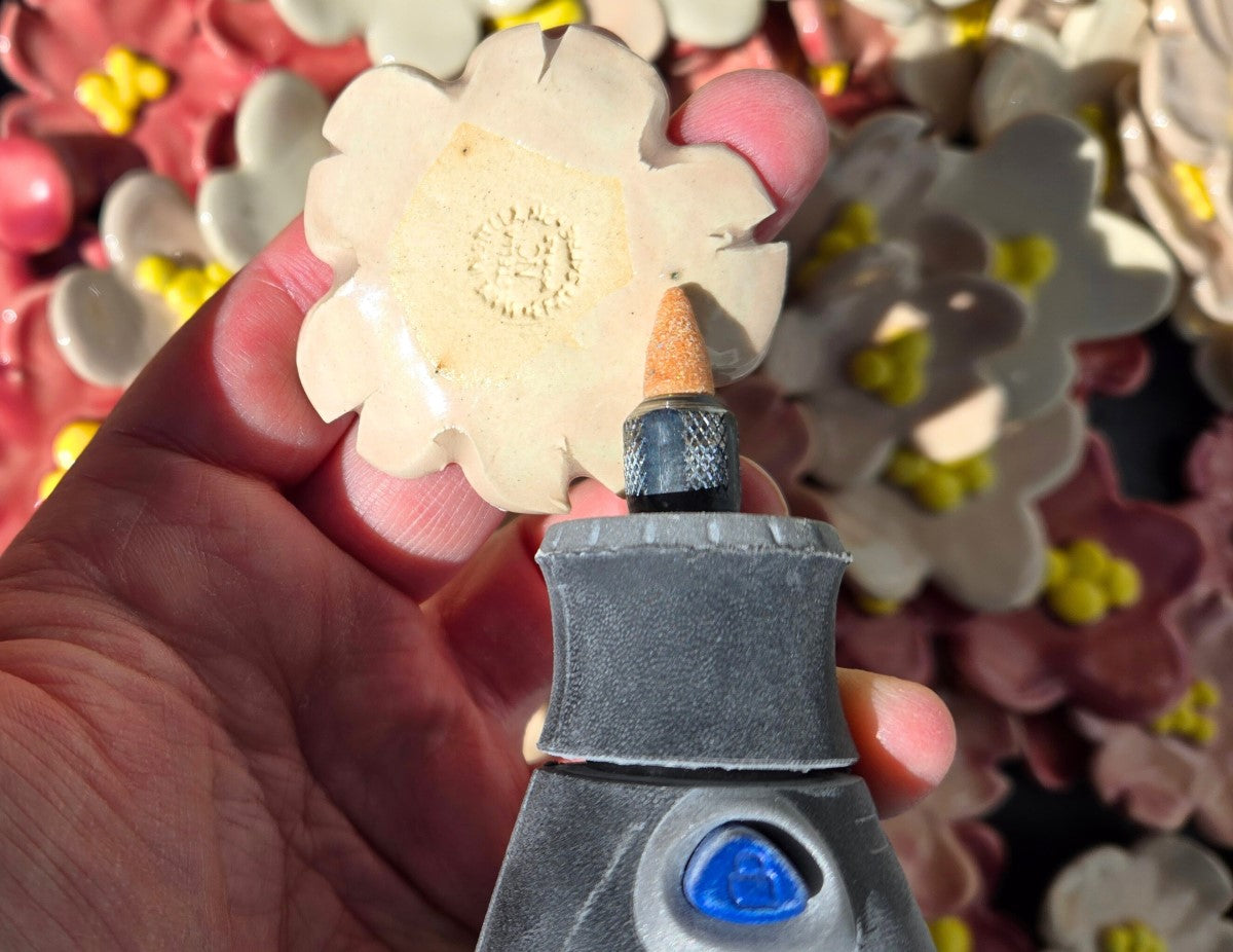 The image shows a Dremmel grinding a black point on the back of a flower.