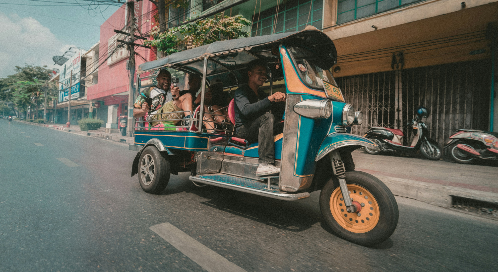 Tuk Tuk racing down the street with a couple laughing in the back.