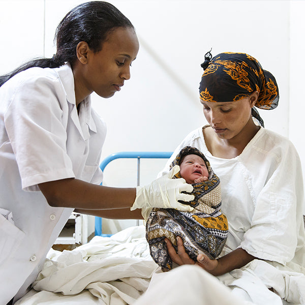 Eine Hebamme in Wolisso, Äthiopien, betreut eine Mutter und ihr Neugeborenes. 