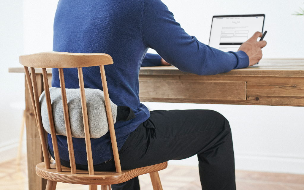 Man sitting on a chair with a heat bag on his back