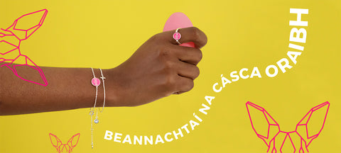 Happy Easter in Irish. A hand adorned with pog bracelet, holding an Easter egg