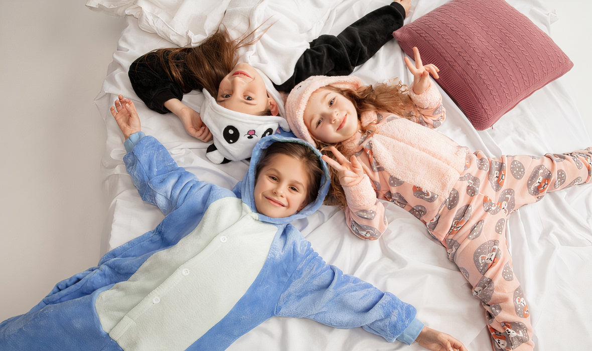 Trois enfants en combinaison pyjama sur un lit