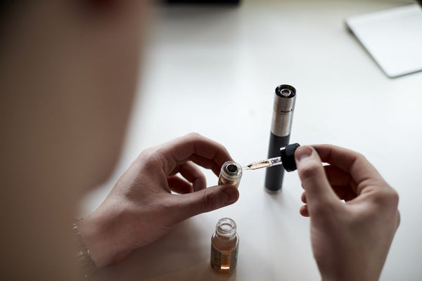 Seorang wanita mengisi ulang cartridge pod dengan liquid vape menggunakan pipet