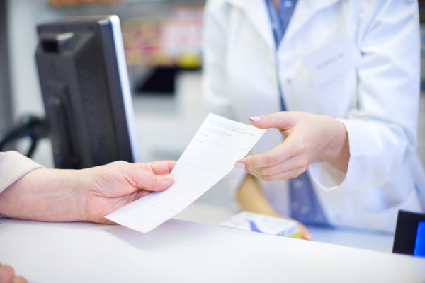 Close up of a prescription being passed to a pharmacist