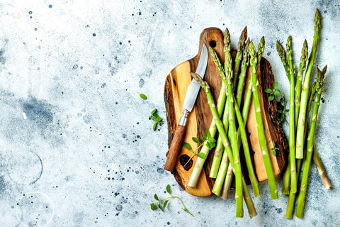 Bouquet d'asperges vertes fraîches sur planche de bois avec assaisonnements