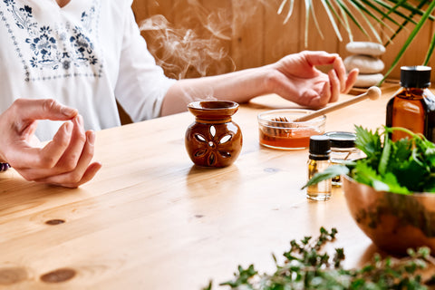 Woman has aromatherapy session at the table with essential oil diffuser medical herbs