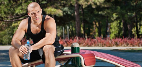 man drinking water resting in between sets of Calisthenics exercise