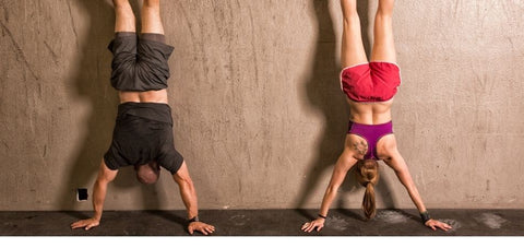 a man and a lady doing wall handstands