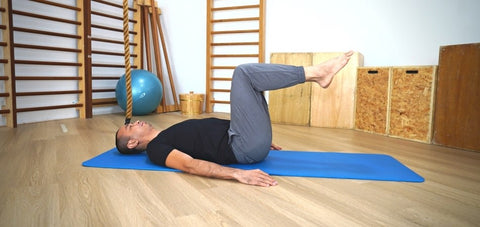 Michel demonstrating supine spine twist on the mat