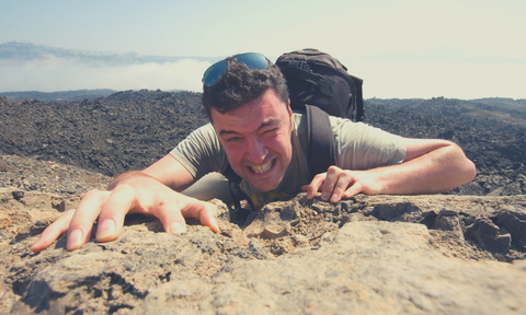 a man struggling to climb, a sign of pushing too hard in training beyond what the body can handle 