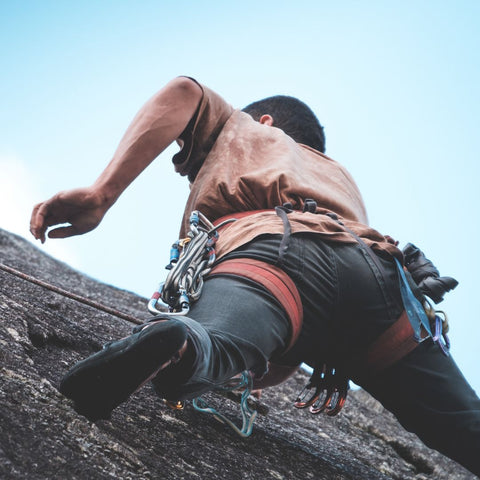 Mann beim Klettern an Felswand, Klettern Handpflege