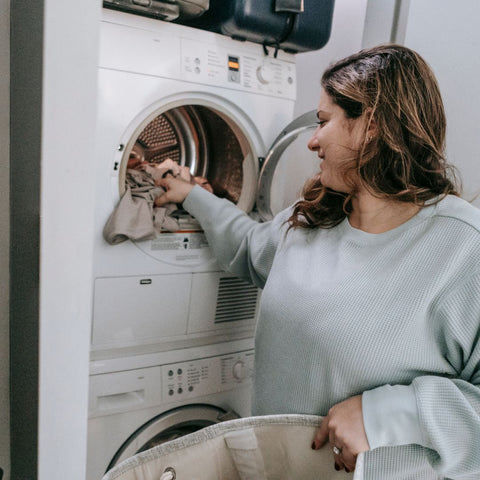 Frau gibt Kleidung in Waschmaschine