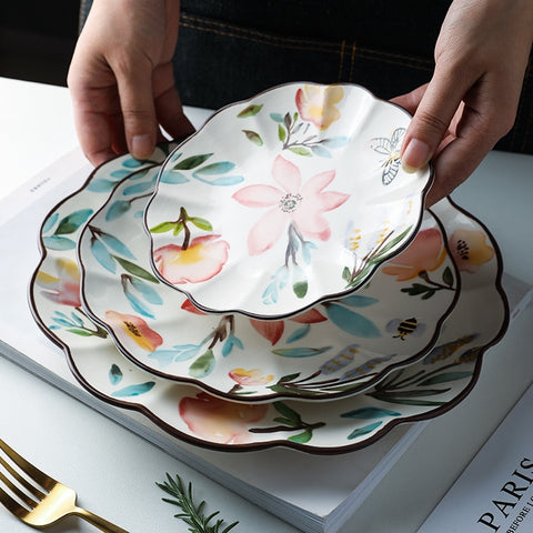 Allthingscurated’s Camille dinnerware features hand-painted florals, fauna and pretty butterflies and a color scheme of pink, yellow, blue,green and brown against a white ceramic background. Every plate is designed with a brown-lined scallop edge. Available in 6, 8 and 10 inches or 15.5, 20 and 25.5cm.