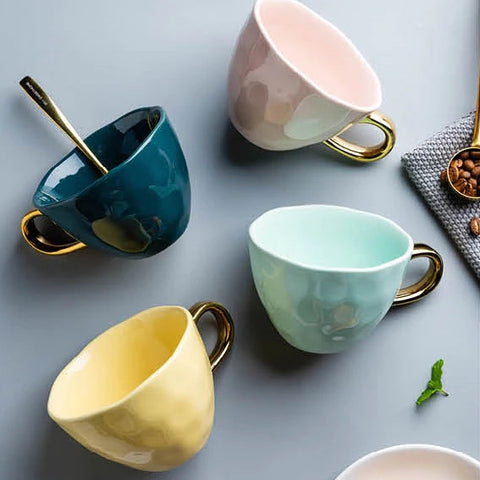 Allthingscurated colorful glazed porcelain cups with gold handle. Designed with a slight all-over concave effect surface that is unique. Available in pink, green, gray, yellow and teal with a capacity of 360ml or 12 ounce.