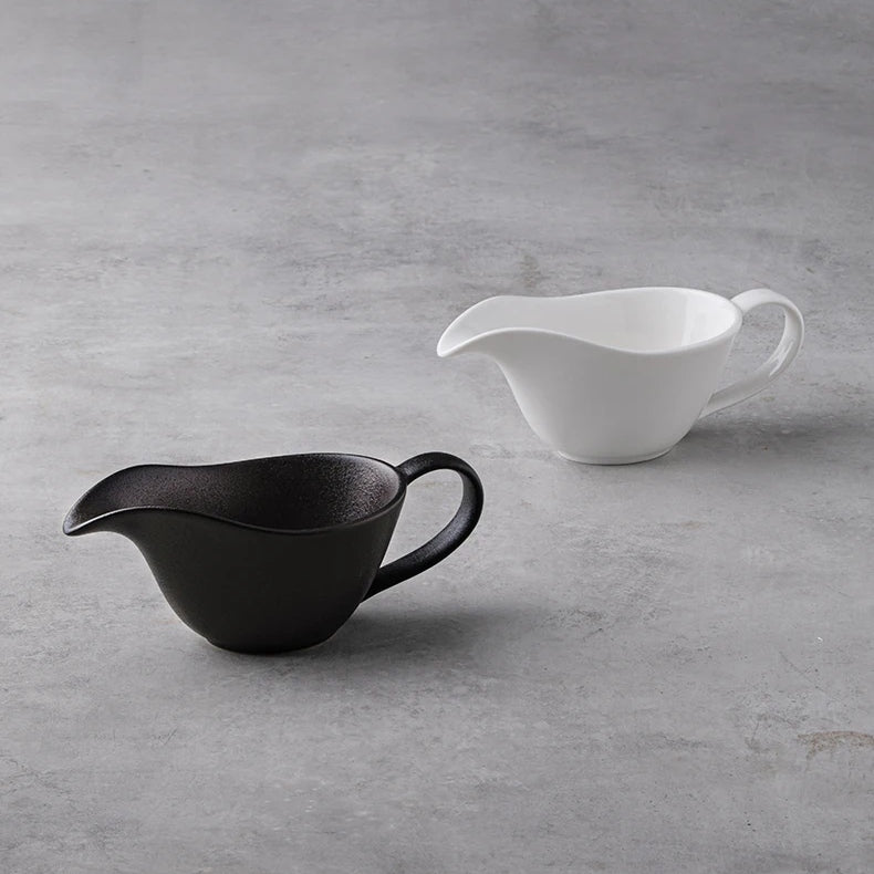 Curtis Ceramic Gravy Boat by Allthingscurated features an easy-to-hold handle and a narrow spout to ensure precise pouring without spills and drips. Available in white with a smooth, shiny glaze or black with a matte, rough finish. This versatile serveware with a capacity of 220ml or 7.4 fluid ounce is perfect for any occasion, formal or casual. 