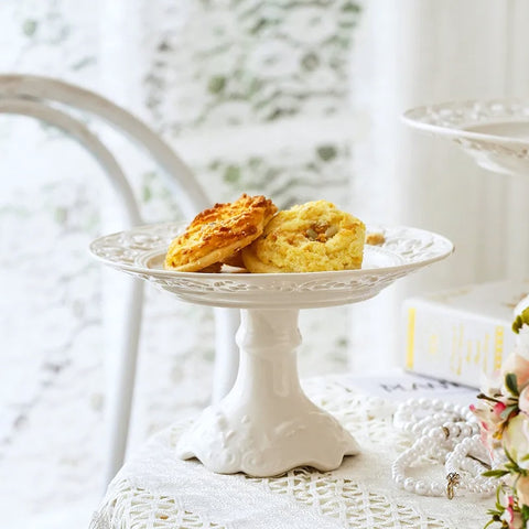 Juliette White Lace Dinnerware by Allthingscurated adds an elegant touch to your tabletop. This sophisticated set is crafted out of ceramic with a beautiful embossed lace rim, giving it a vintage touch.  The creamy white pieces come in a dinner plate and cake stand in 2 sizes for easy mixing and matching. They are perfectly sized for a main course, starters and desserts.