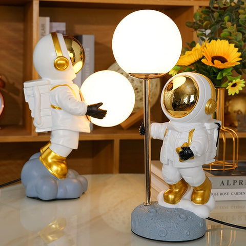 Two astronauts in white space suit. One holding moon in both hand and another holding to a pole with moon attached on top. Astronaut Moon Lamps by Allthingscurated.