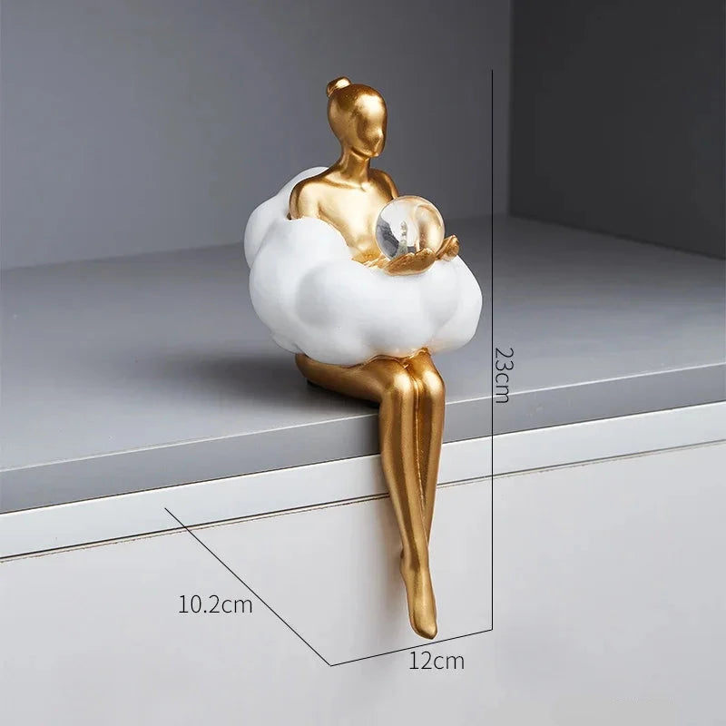 Sophie Cloud Girl Sculptures by Allthingscurated feature 2 beautiful lady statues in 2 postures—reading and pondering. Adorned with a classic ballerina bun and dressed in a minimalistic dress that ends with a voluminous skirt reminiscent of fluffy clouds. These sculptures bring a touch of serenity and sophistication to your living space. Featured here is the lady pondering with a faux crystal ball in hands.