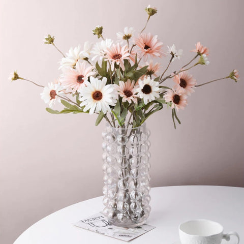 Zayla Bubble Vase by Allthingscurated features a geometric bubble design. The eye-catching detail and design are enough to make it a statement centerpiece with or without floral display. Comes in black or clear and in 2 sizes. The short vase measures 17cm or 6.6 inches in height and 16cm or 6.2 inches in diameter.  The tall vase measures 27.5cm or 10.7 inches in height and 13cm or 5 inches in diameter. This is a clear tall vase with beautiful and colorful daisies.