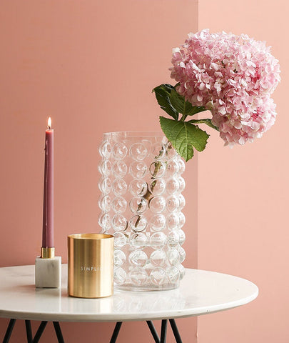 Zayla Bubble Vase by Allthingscurated features a geometric bubble design. The eye-catching detail and design are enough to make it a statement centerpiece with or without floral display. Comes in black or clear and in 2 sizes. The short vase measures 17cm or 6.6 inches in height and 16cm or 6.2 inches in diameter.  The tall vase measures 27.5cm or 10.7 inches in height and 13cm or 5 inches in diameter. This is a tall clear vase with a sprig of pink hydrangea.