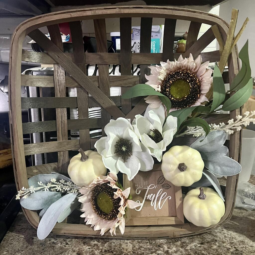 Decorative basket with fall flowers, pumpkins, and a 'Hello Fall' sign.