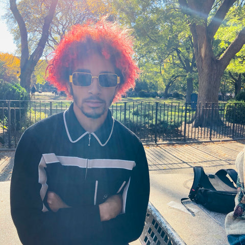 man with red hair wearing brown and gold square sunglasses in a park