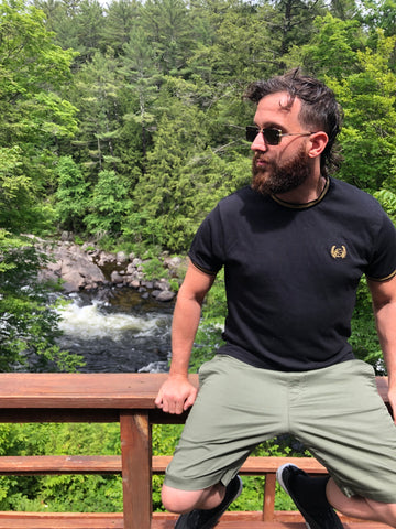 man sitting on railing wearing in front of river wearing black sunglasses